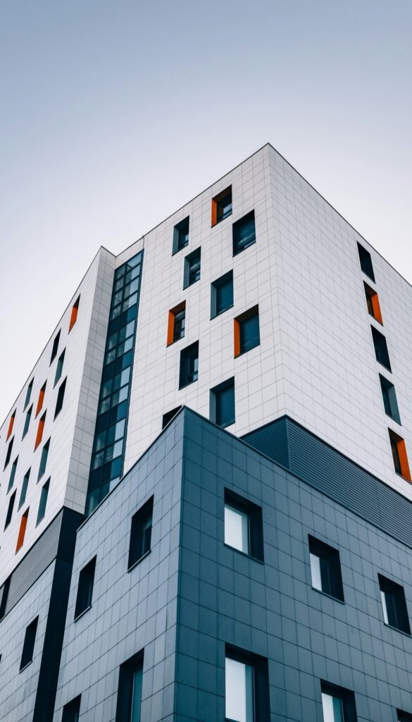 A modern building with white and grey tiled facades and orange window accents