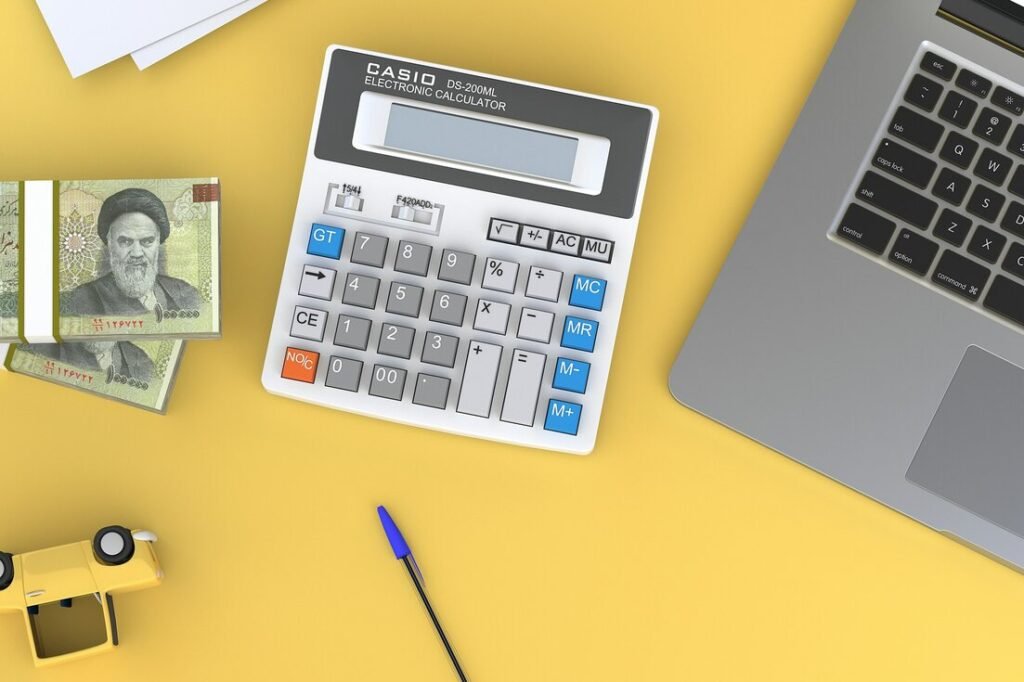 A calculator sitting on top of a desk next to a laptop