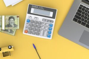 A calculator sitting on top of a desk next to a laptop