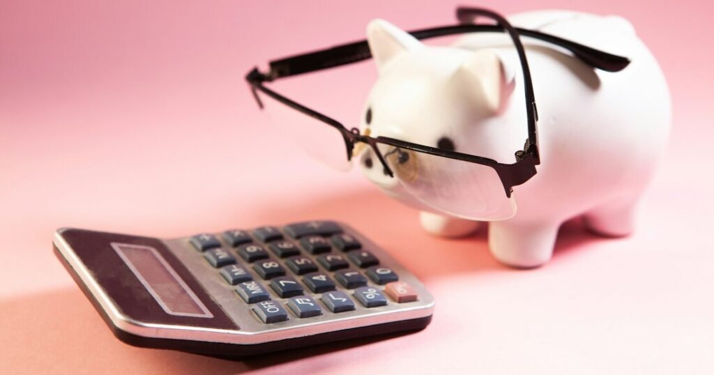 A piggy bank wearing glasses next to a calculator