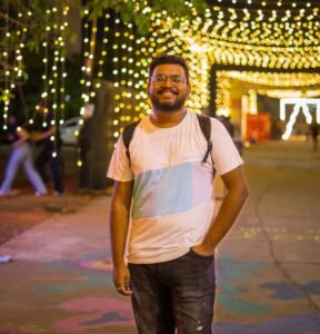 A man standing on a sidewalk in front of some lights