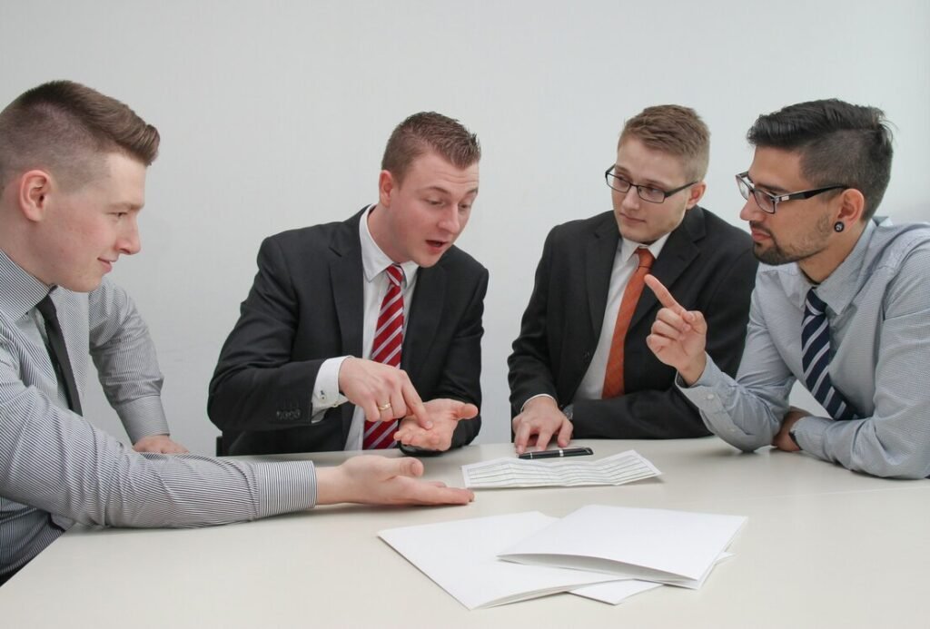 Four men sitting at desk talking