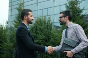 Two businessmen shaking hands outside modern building
