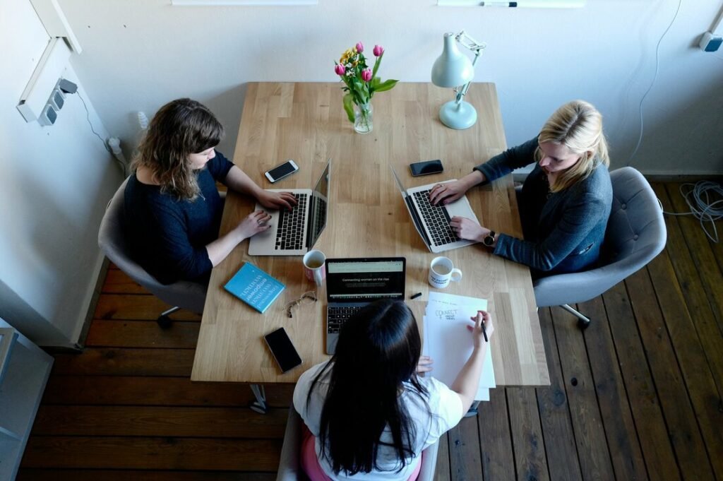 Three women sitting around table using laptops