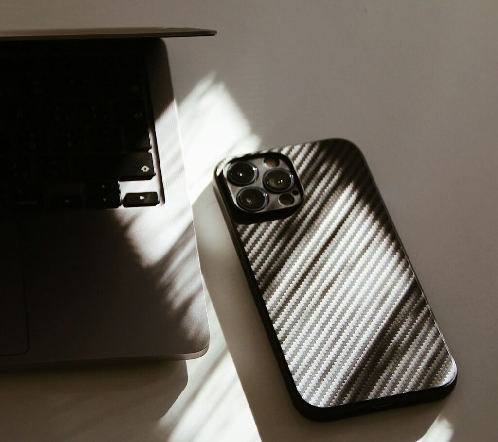 A cell phone sitting on top of a table next to a laptop
