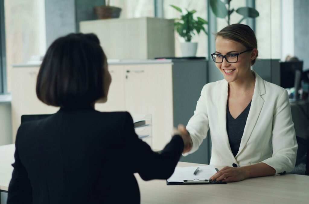 Two women shaking hands across a desk