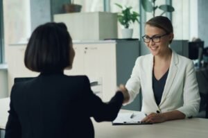 Two women shaking hands across a desk