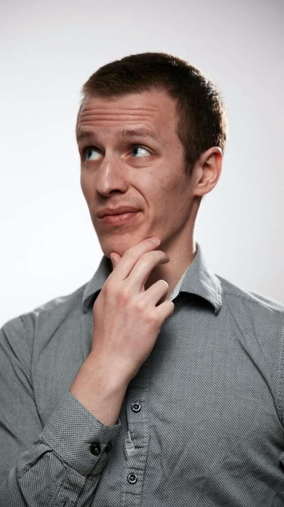 Man in a gray shirt with his hand on his chin, thinking