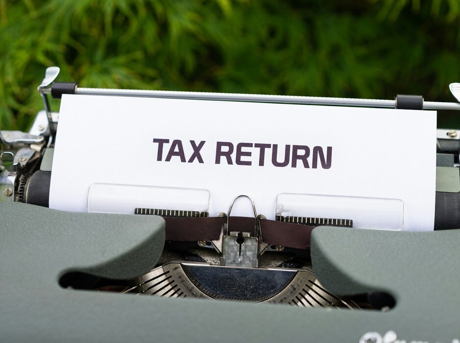 A close up of a typewriter with a tax return sign on it