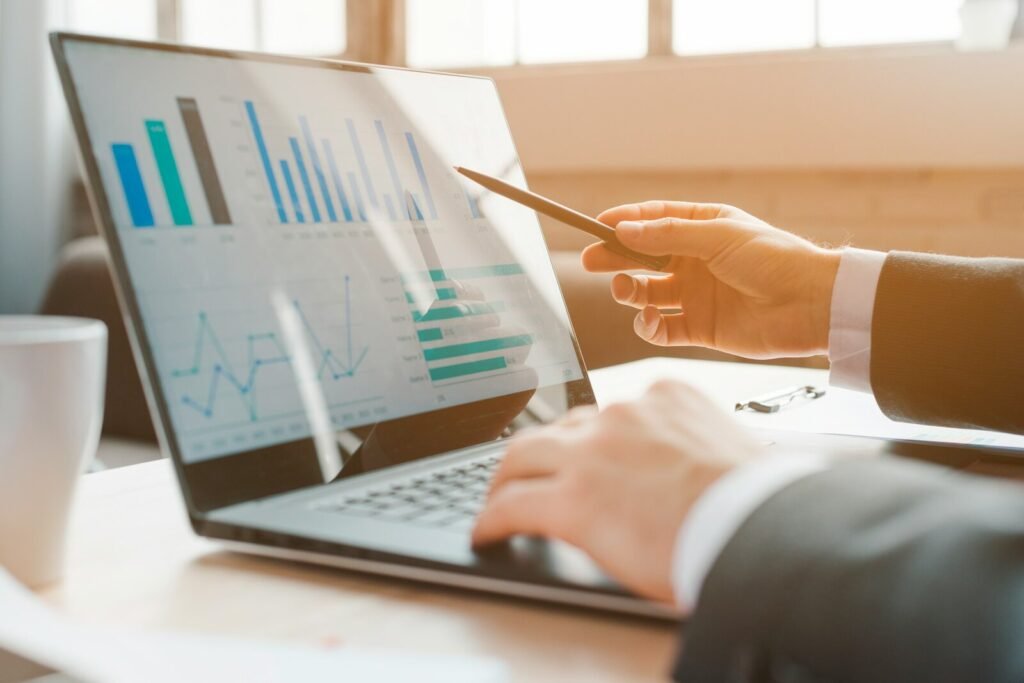 Hands working on a laptop showing charts and analytics while a colleague points at the screen