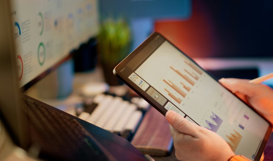 Hands using a tablet showing charts in an office