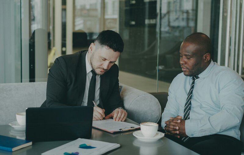 Two businessmen signing a document at a table