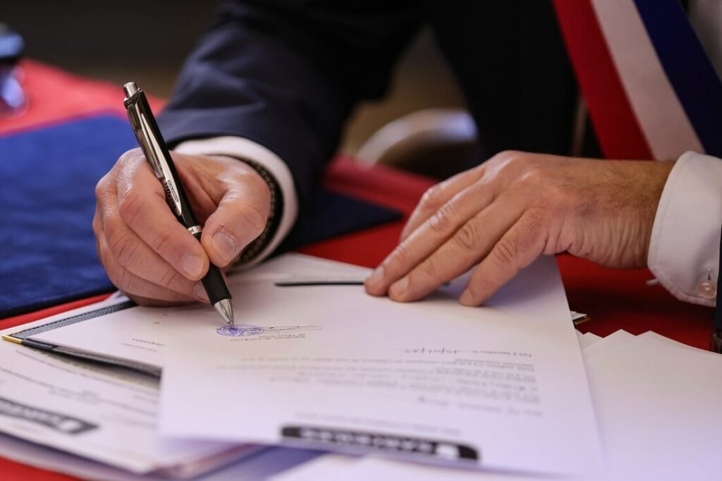 A person signs a document with a pen