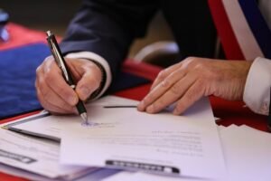 A person signs a document with a pen