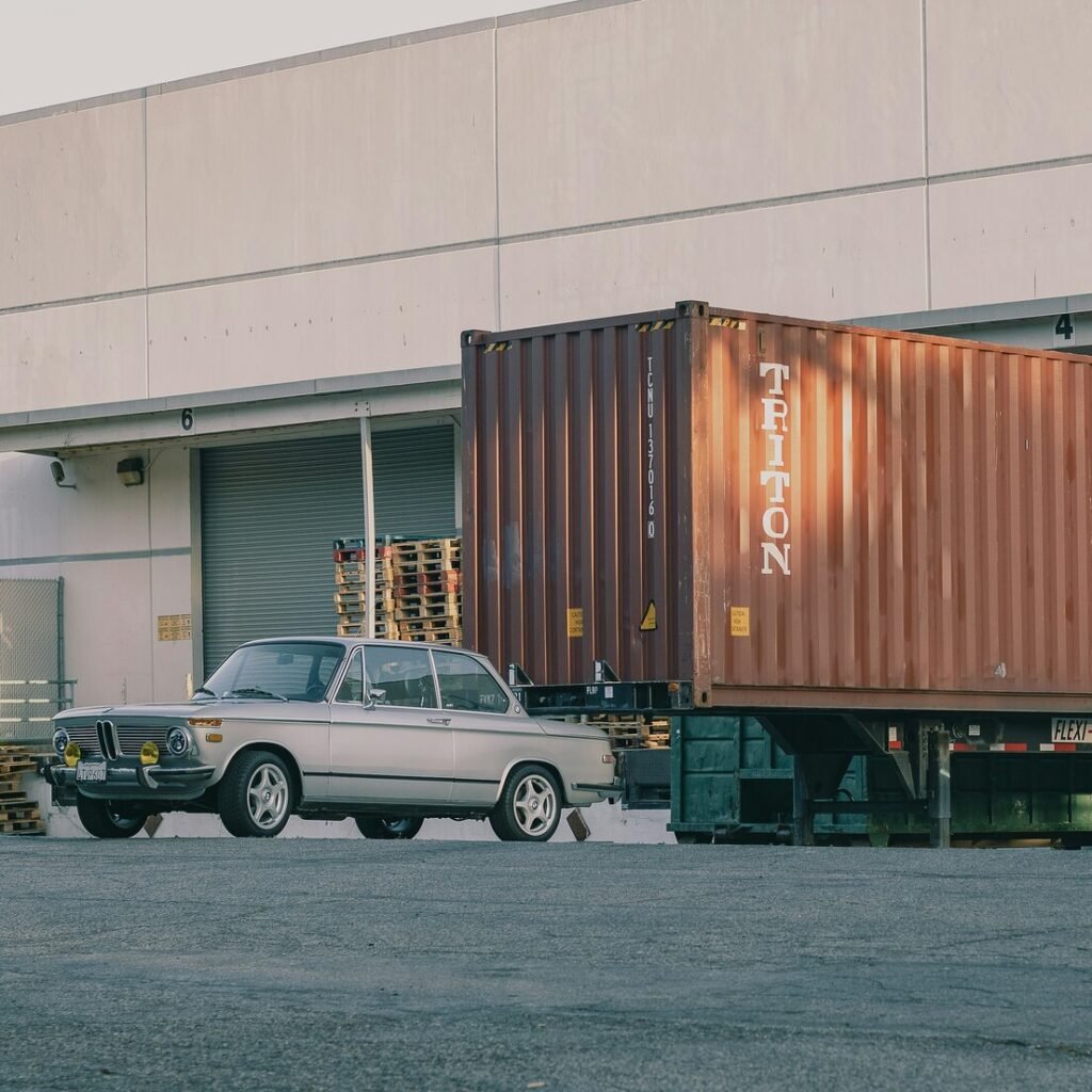 A car is parked in front of a shipping truck