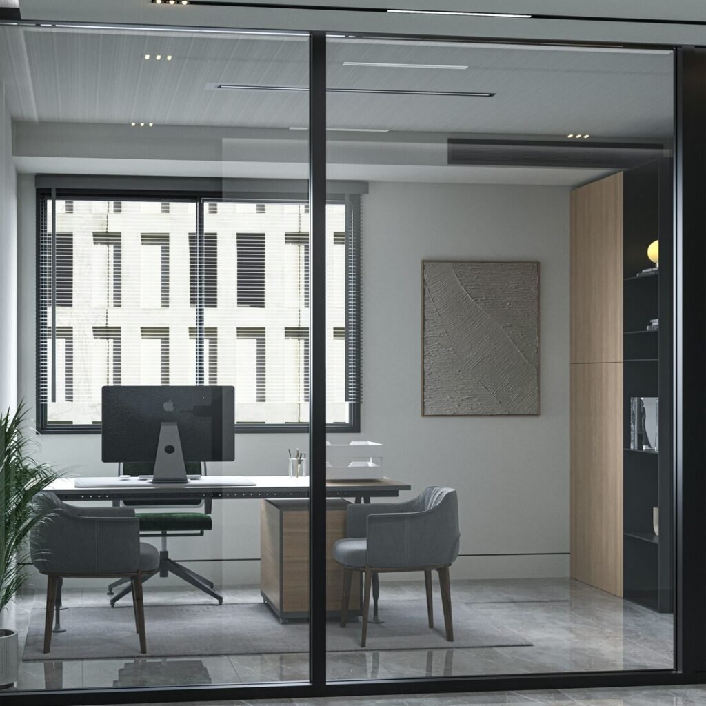 A glass walled office with a desk and chairs