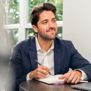 Man in black suit jacket holding pen