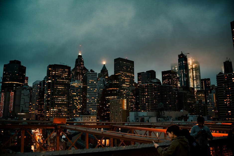 Man in white shirt sitting on red metal bridge during night time