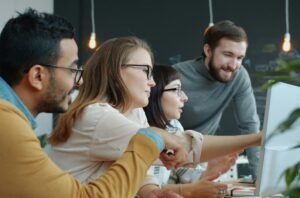 Diverse team collaborating around a computer screen