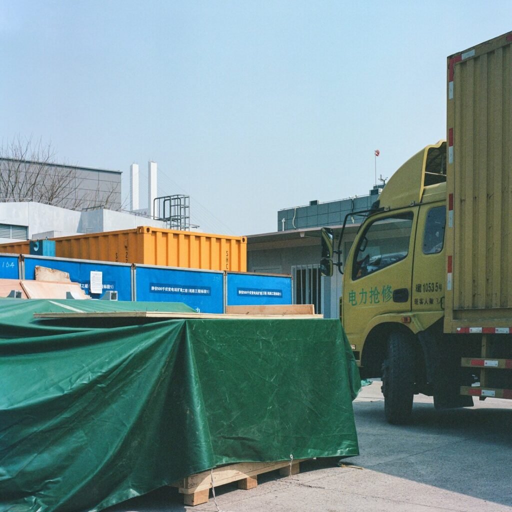 A yellow truck with a green tarp on the back of it