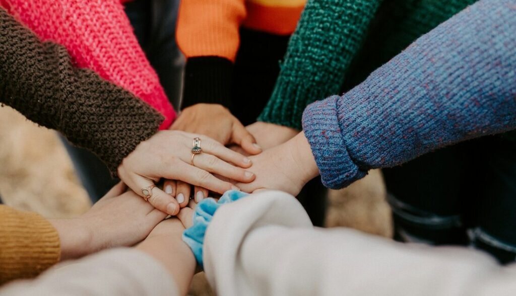 Group stacking hands in colorful sweaters