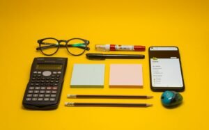 A calculator, pen, eyeglasses, notepad, pencils