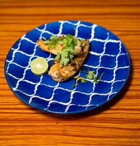A blue plate topped with chicken covered in cilantro