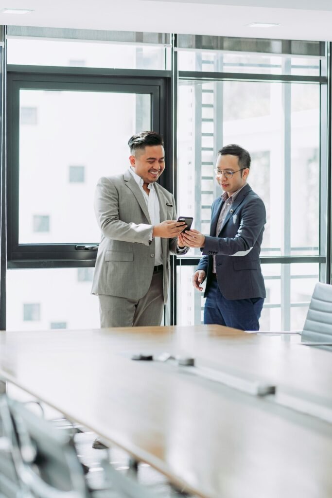 Two businessmen looking at phone in office