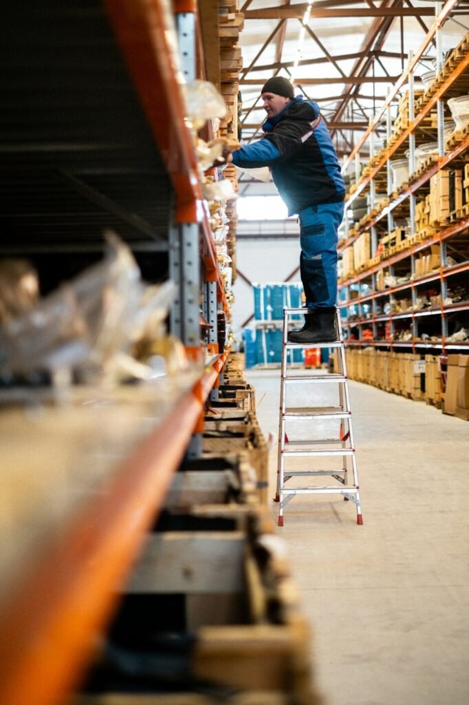 A man standing on a ladder in a warehouse