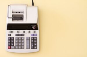 A grey printing calculator on a light yellow background