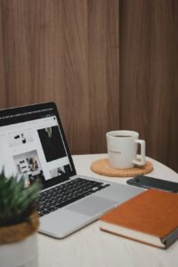 Macbook pro beside white ceramic mug on brown wooden table