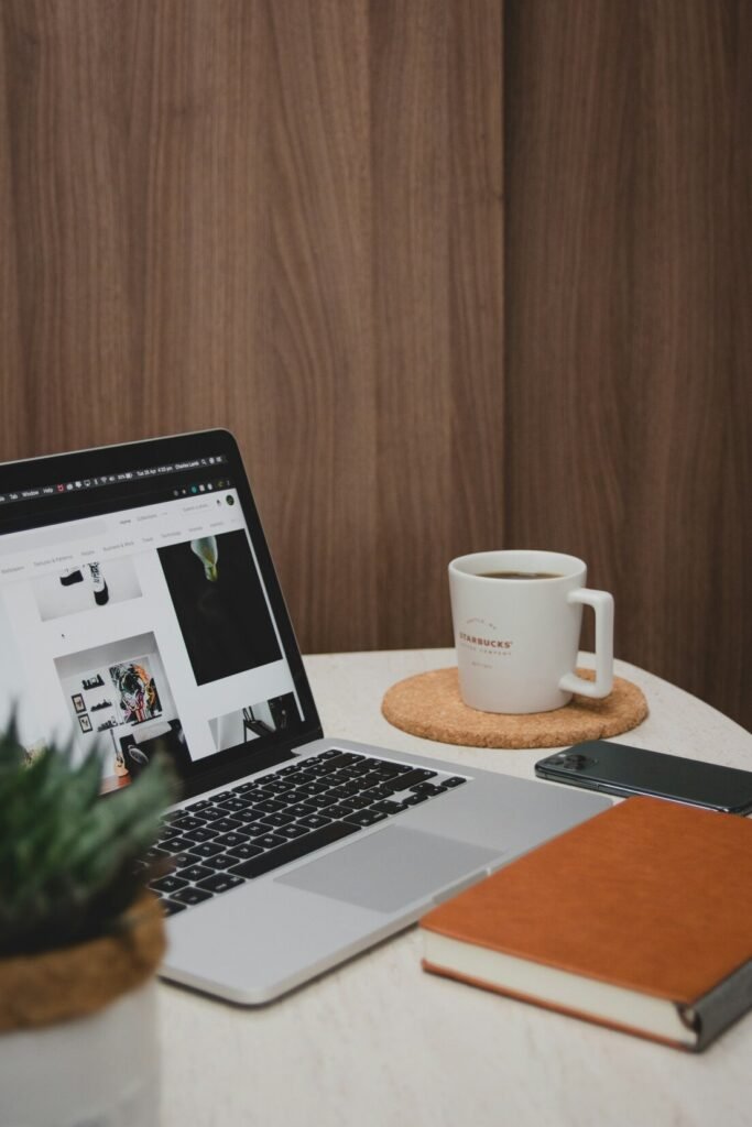 Macbook pro beside white ceramic mug on brown wooden table