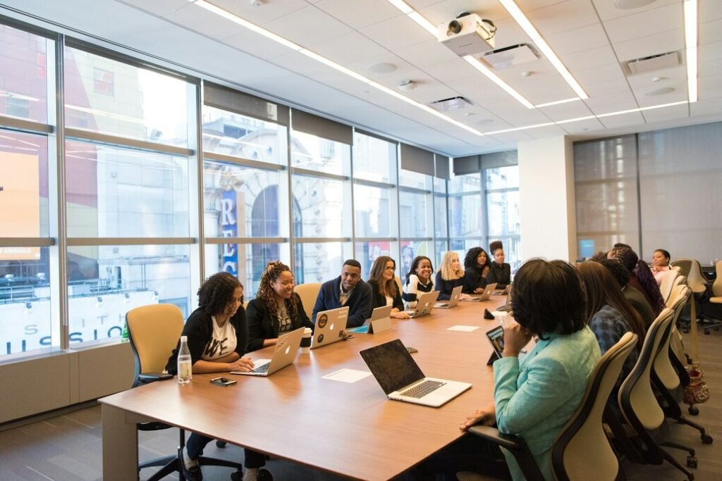 Group of people sitting beside rectangular wooden table with laptops