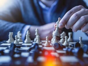 Hand moving a chess piece on a chessboard, illustrating strategy
