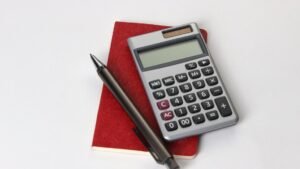 Black and silver calculator beside black pen