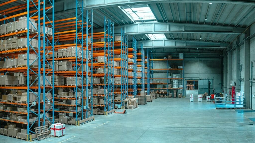 Tall blue metal shelving units filled with cardboard boxes in a large warehouse