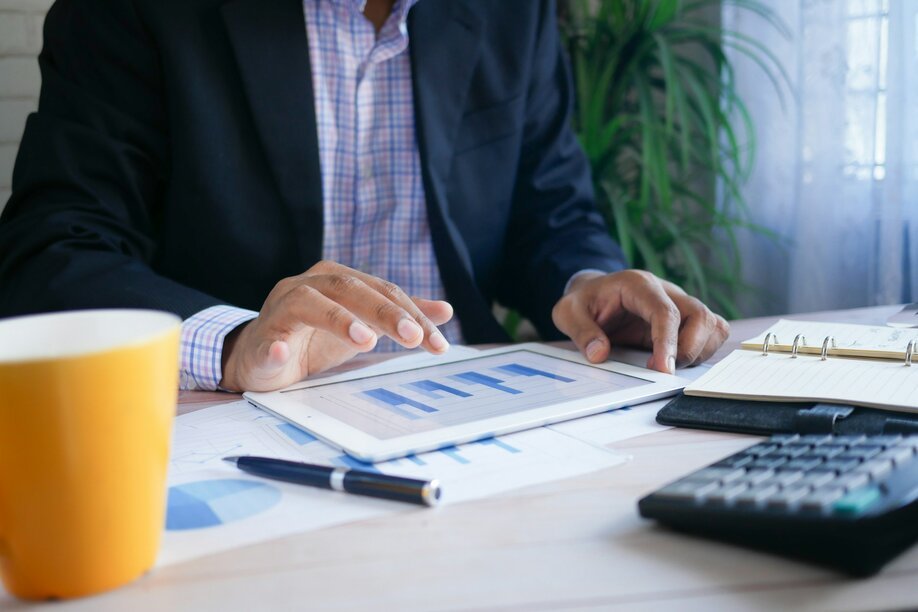 Businessman reviewing financial charts on a tablet at a desk with a calculator
