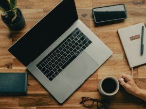 Macbook pro beside black iphone 5 on brown wooden table