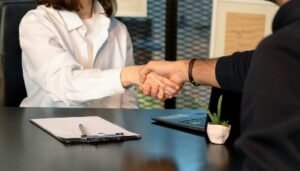 A man and a woman shaking hands in front of a laptop