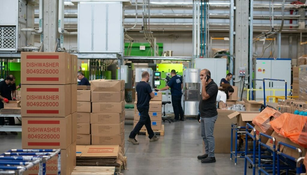 Man in gray shirt standing beside brown cardboard boxes