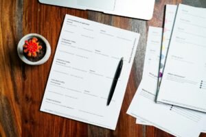 Paper forms and a pen on a wooden desk