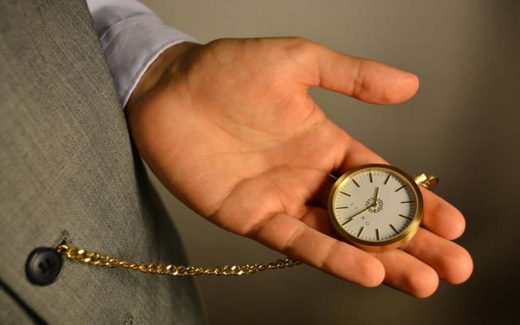Hand holding a pocket watch, illustrating time