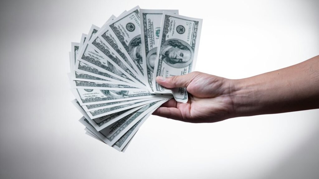 Hand holding a fan of US dollar bills