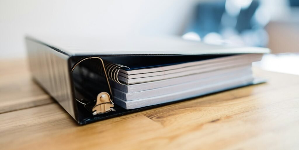 Black document binder on a wooden desk