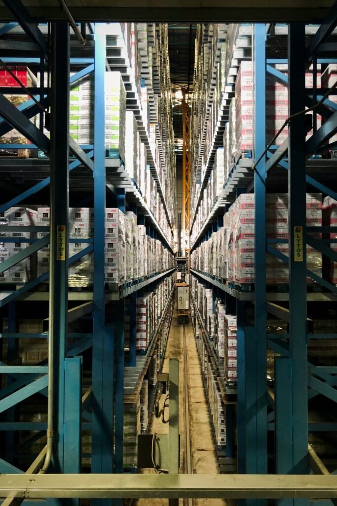 Tall blue metal shelving units filled with stacked boxes in a warehouse aisle